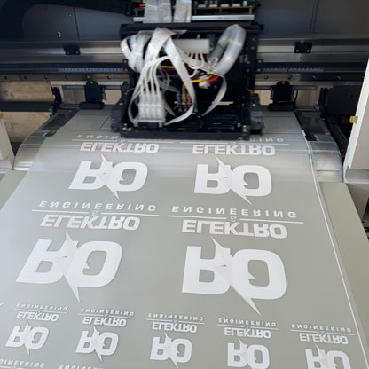 Printing process with a machine applying white text and logo onto gray material.
